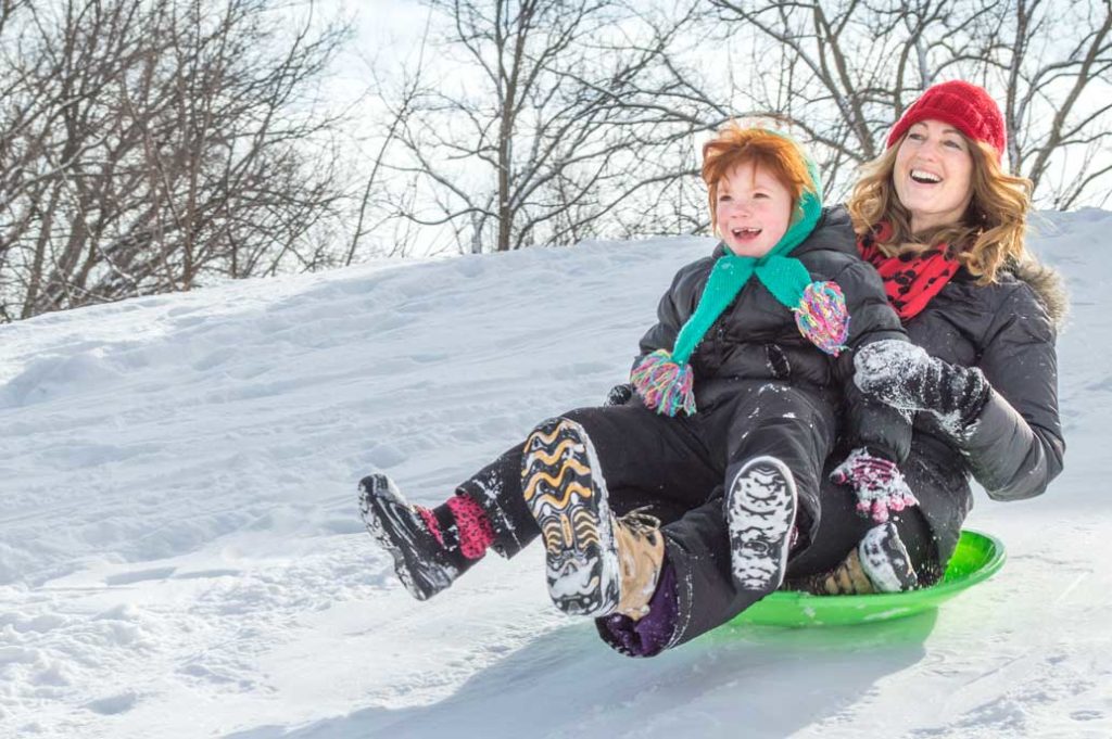A woman and young child sledding.
